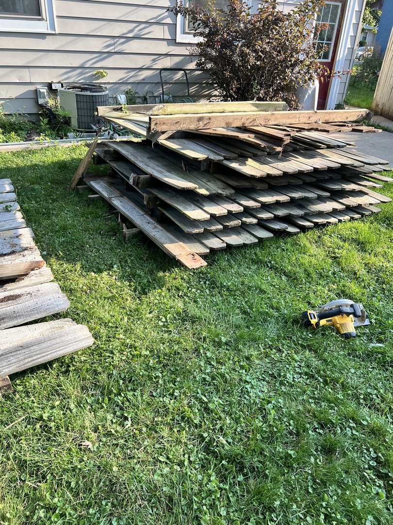 Stacked wood fence boards next to a circular saw